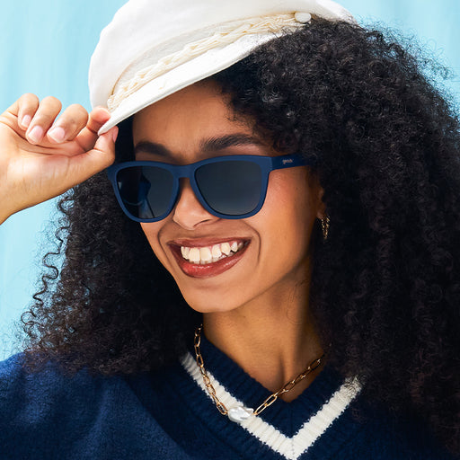 A stylish woman beams in navy blue sunglasses with gradient blue lenses.
