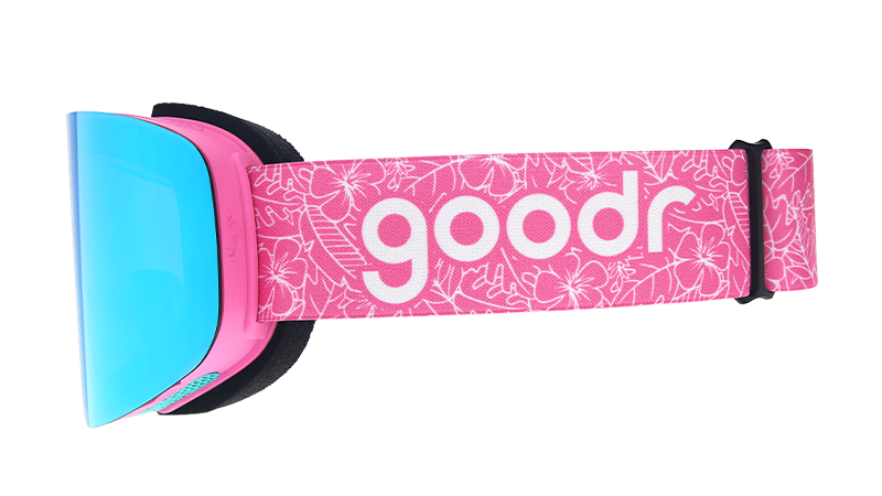 Side view of pink & blue snow goggles with blue reflective lens & pink strap with goodr logo over outlined tropical print.