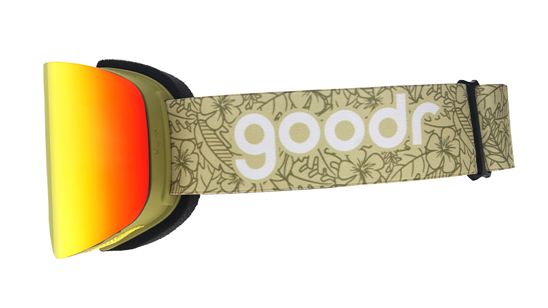 Side view of snow goggles with a reflective orange lens and olive green strap with the goodr logo and a faint tropical print.