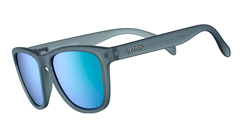 Three-quarter angle view of square-shaped sunglases with a gray translucent frame and green reflective lenses.