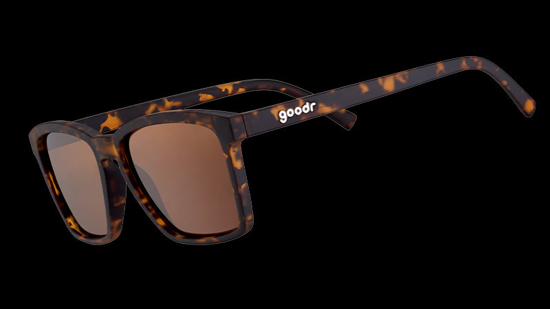Three-quarter angle view of slim-fit tortoiseshell sunglasses with square non-reflective brown lenses.