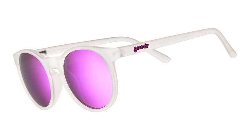 Three-quarter angle view of clear sunglasses with round reflective purple lenses.