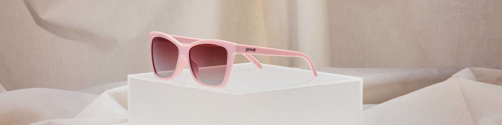 Pink-framed sunglasses with red lenses on a light background.