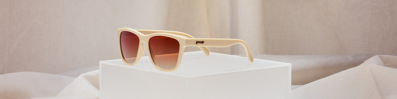 Cream-colored goodr sunglasses on a white surface.