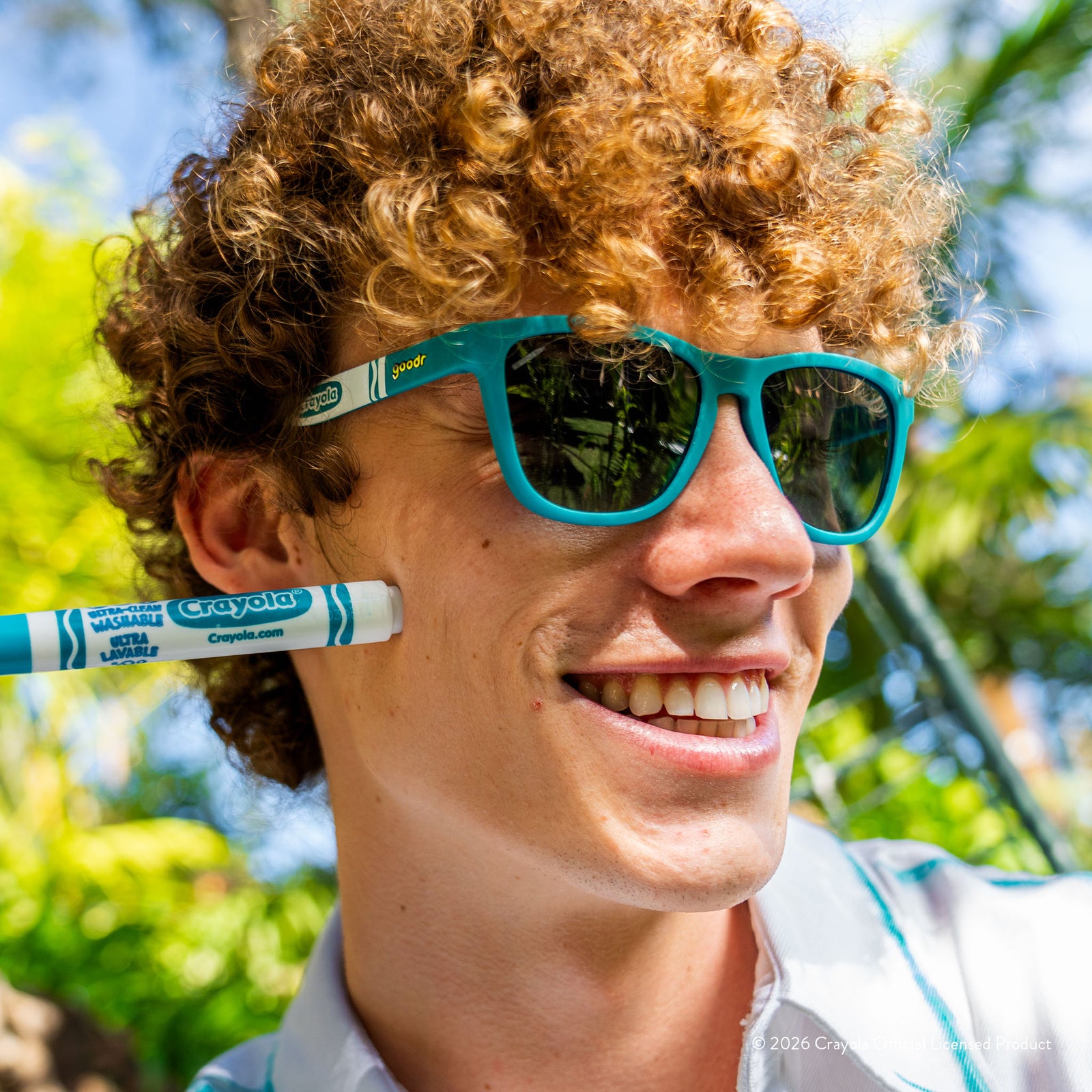 Man wearing turquoise sunglasses w/ white Crayola marker pattern+green gradient lenses smiling in a tropical setting.