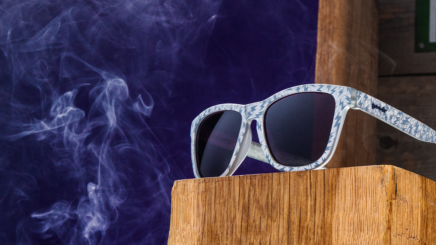 White sunglasses with blue lightning bolts surrounded by white smoke.