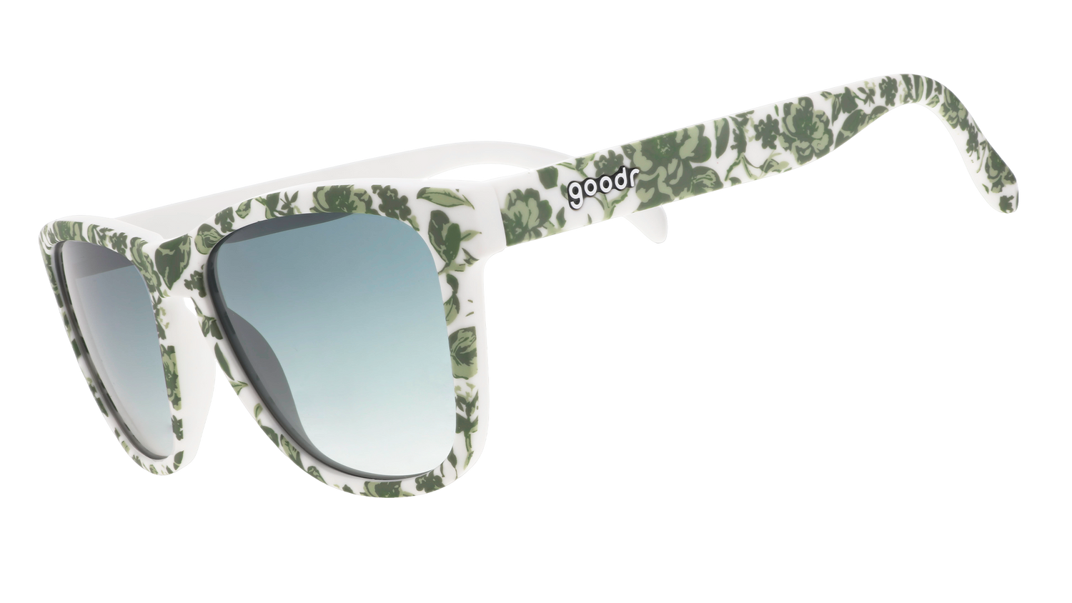 Three-quarter angle view of sunglasses with a green and white floral toile and green gradient lenses.