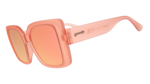 Three-quarter angle view of oversized square sunglasses in coral pink with champagne gold reflective lenses.