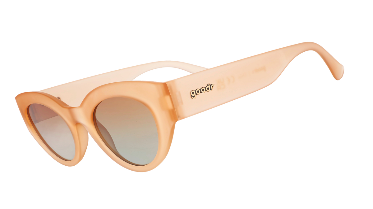 Three-quarter angle view of translucent peach cat-eye sunglasses with orange gradient lenses and the goodr logo in frame.