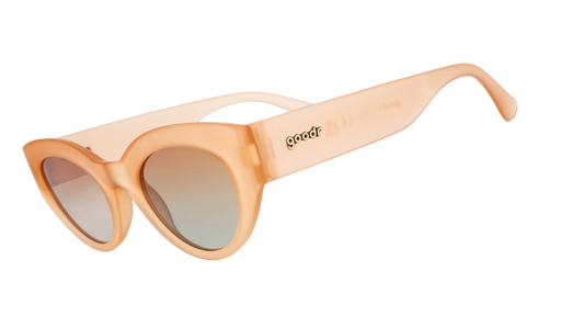 Three-quarter angle view of translucent peach cat-eye sunglasses with orange gradient lenses and the goodr logo in frame.
