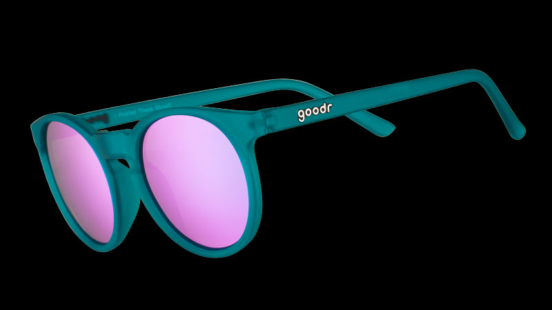 Three-quarter angle view of round teal sunglasses with reflective purple circle-shaped lenses.