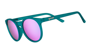 Three-quarter angle view of round teal sunglasses with reflective purple circle-shaped lenses.