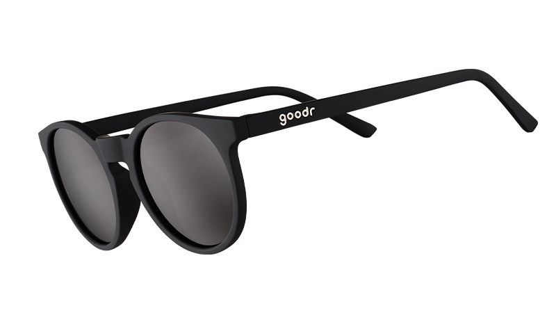 Three-quarter angle view of retro-inspired black round sunglasses with non-reflective black lenses.