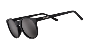 Three-quarter angle view of retro-inspired black round sunglasses with non-reflective black lenses.