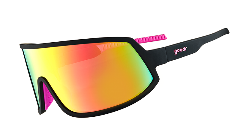 Three-quarter angle view of wraparound sunglasses with black frames with hot pink inner silicone grips, and a big pink lens. 