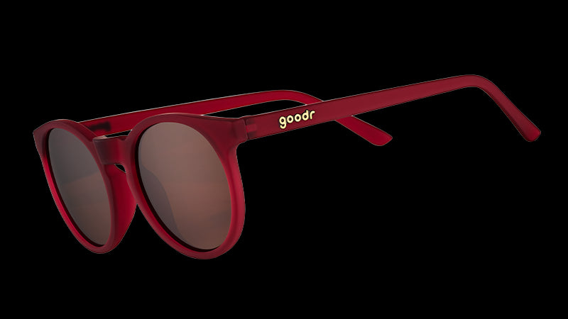 Three-quarter angle view of round burgundy sunglasses with circle-shaped non-reflective brown lenses.