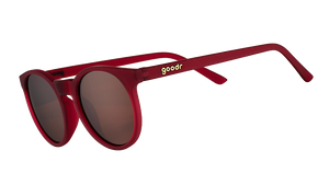 Three-quarter angle view of round burgundy sunglasses with circle-shaped non-reflective brown lenses.