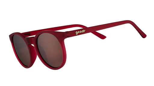 Three-quarter angle view of round burgundy sunglasses with circle-shaped non-reflective brown lenses.