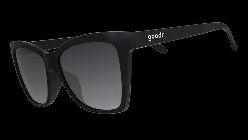 Three-quarter angle view of black angled cat-eye sunglasses with non-reflective black gradient lenses.