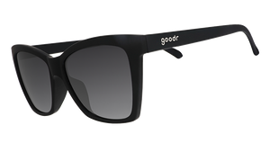 Three-quarter angle view of black angled cat-eye sunglasses with non-reflective black gradient lenses.