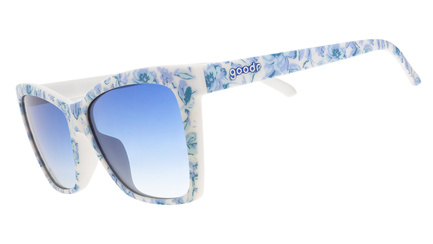 Three-quarter angle view of blue and white angular cat-eye sunglasses with a floral toile and blue gradient lenses.