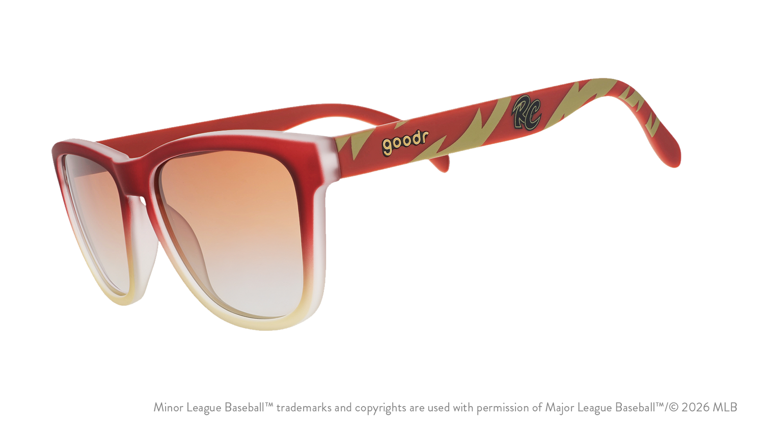 Three-quarter angle view of sunglasses tilted down. Brown + red frames w/ RC on temples + amber gradient lenses.