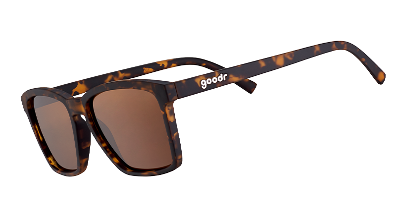 Three-quarter angle view of slim-fit tortoiseshell sunglasses with square non-reflective brown lenses.