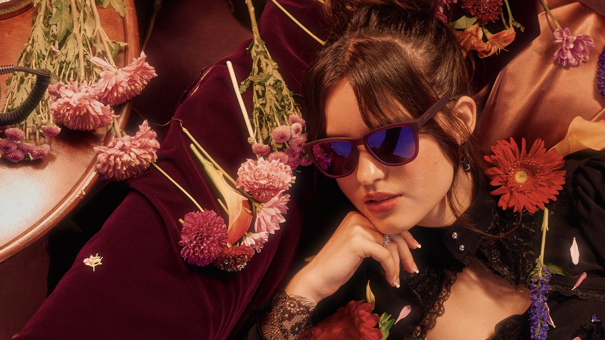 Woman wearing sunglasses with floral and decorative elements in the background