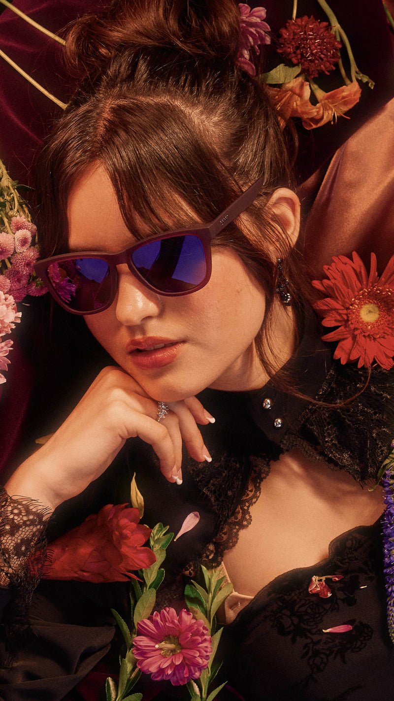 Woman wearing sunglasses with a floral background