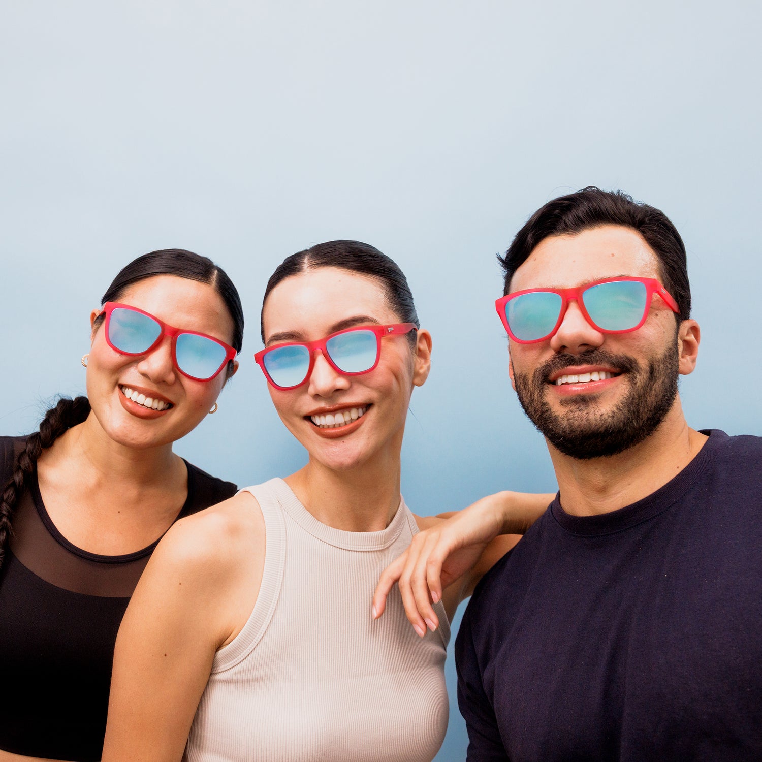 Three people wearing pink Small, Orginal, and Large sized OG goodr sunglasses against a light blue background.