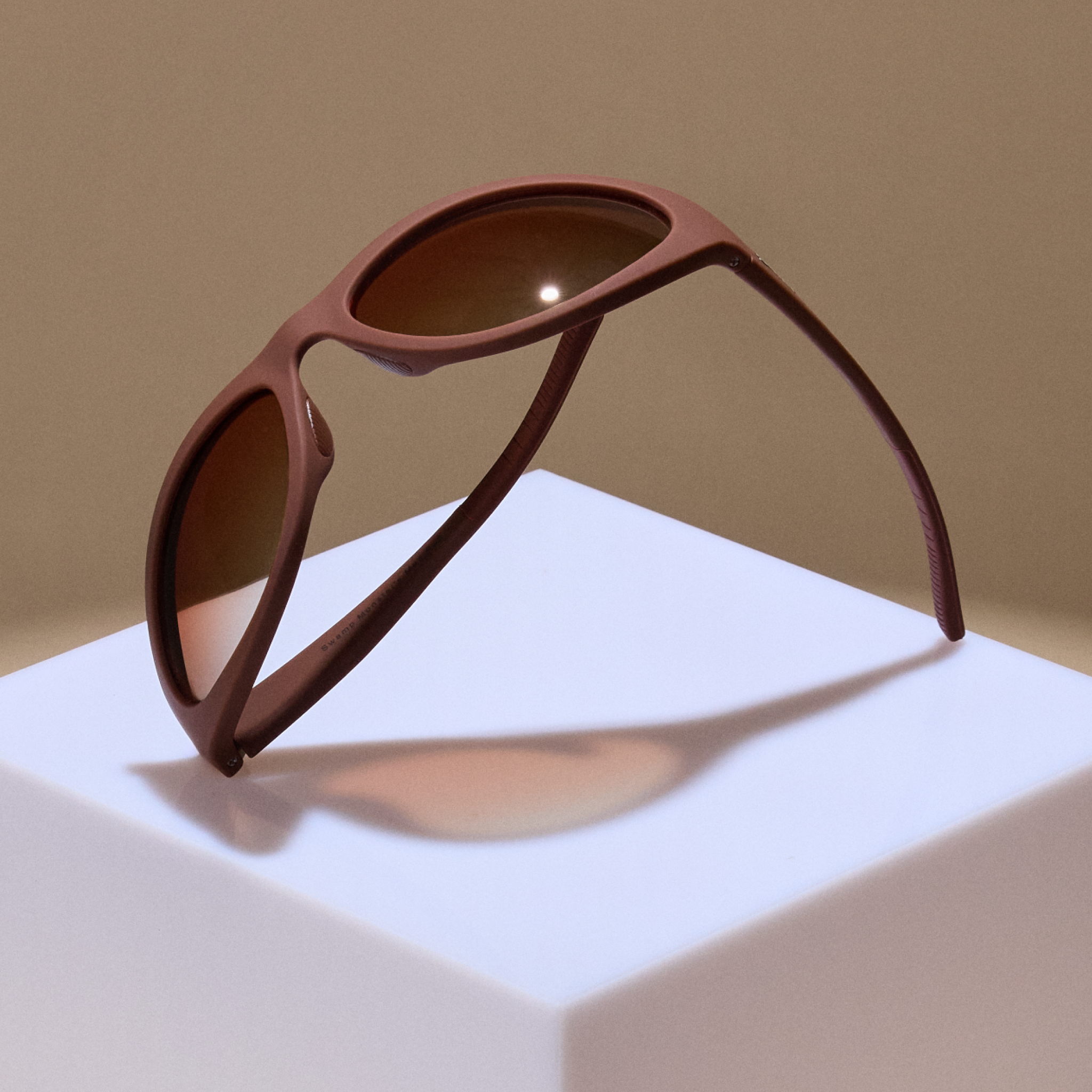 A semi-folded display of brown wraparound sunglasses with brown gradient lenses.