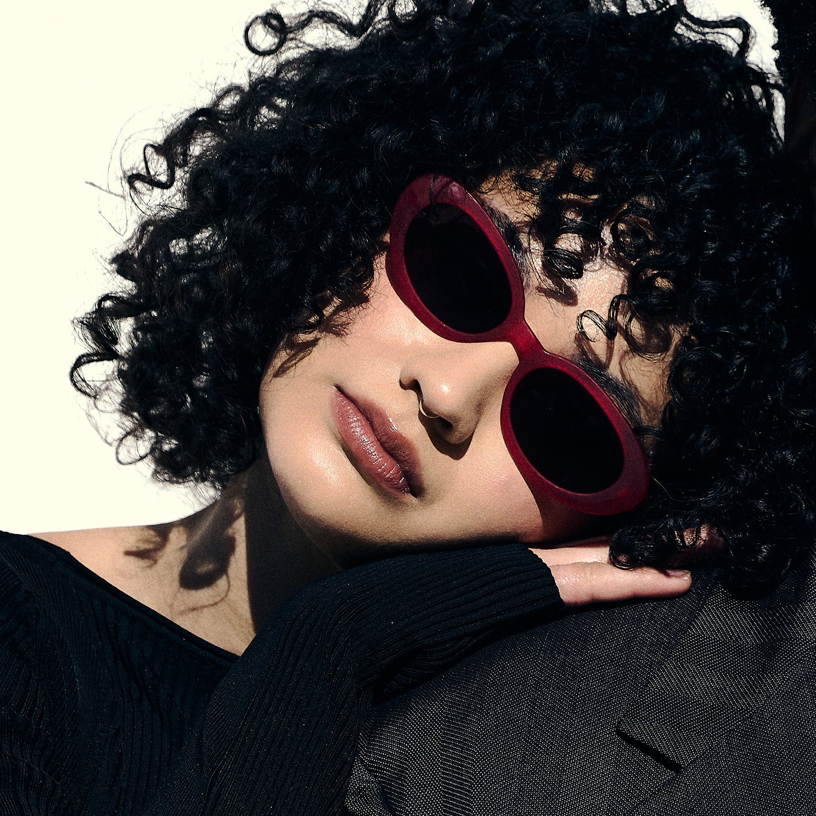 A woman poses while wearing hot pink oval sunglasses with dark red polarized lenses.