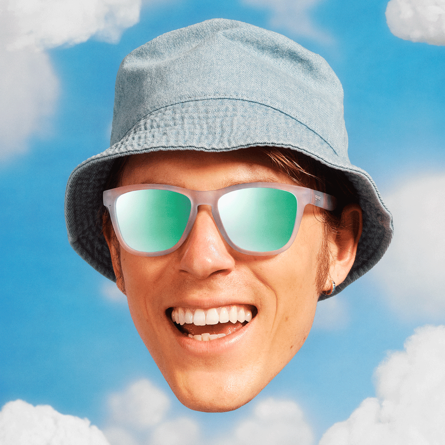 A dude in a bucket hat with a huge smile wears pink sky-themed OG shades against a blue sky backdrop with puffy white clouds.