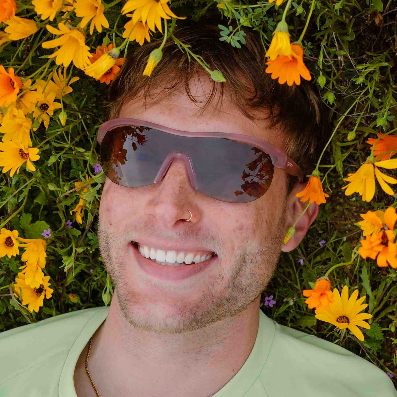 Model outside, smiling while wearing translucent purple wrap shield sunglasses with gradient purple lenses.