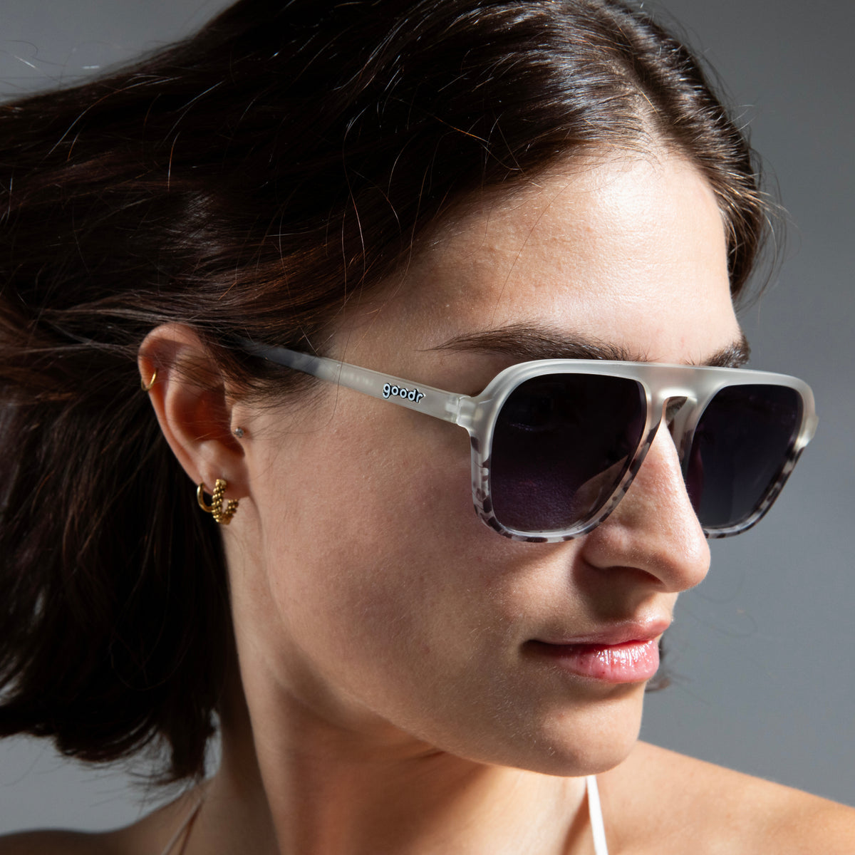 Side profile of a woman wearing translucent gray retro aviator sunglasses with a tonal pattern and black gradient lenses.