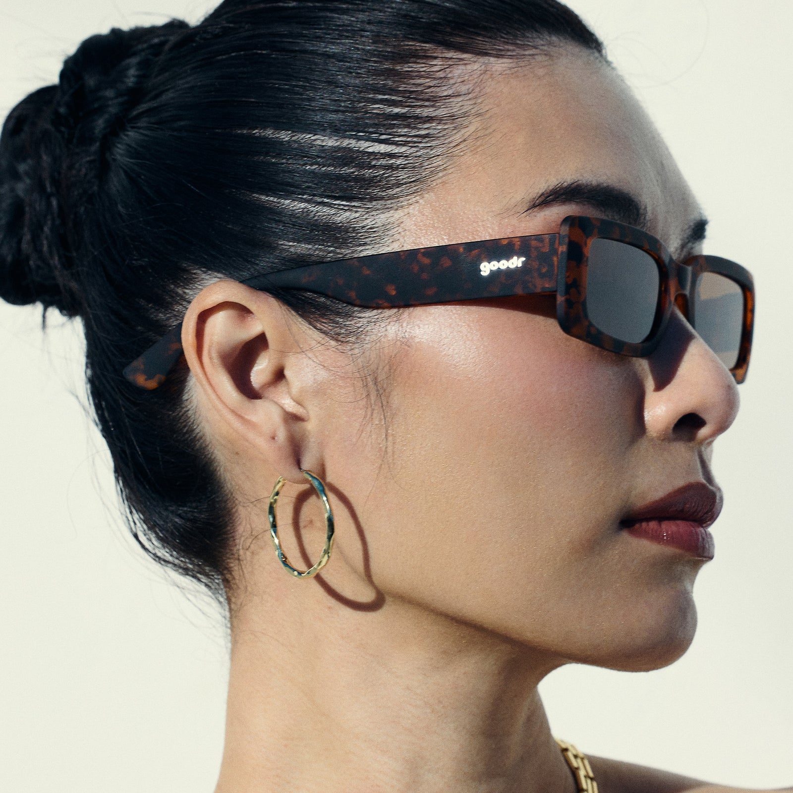 Right profile view of a woman wearing tortoiseshell rectangular sunglasses with brown polarized lenses.