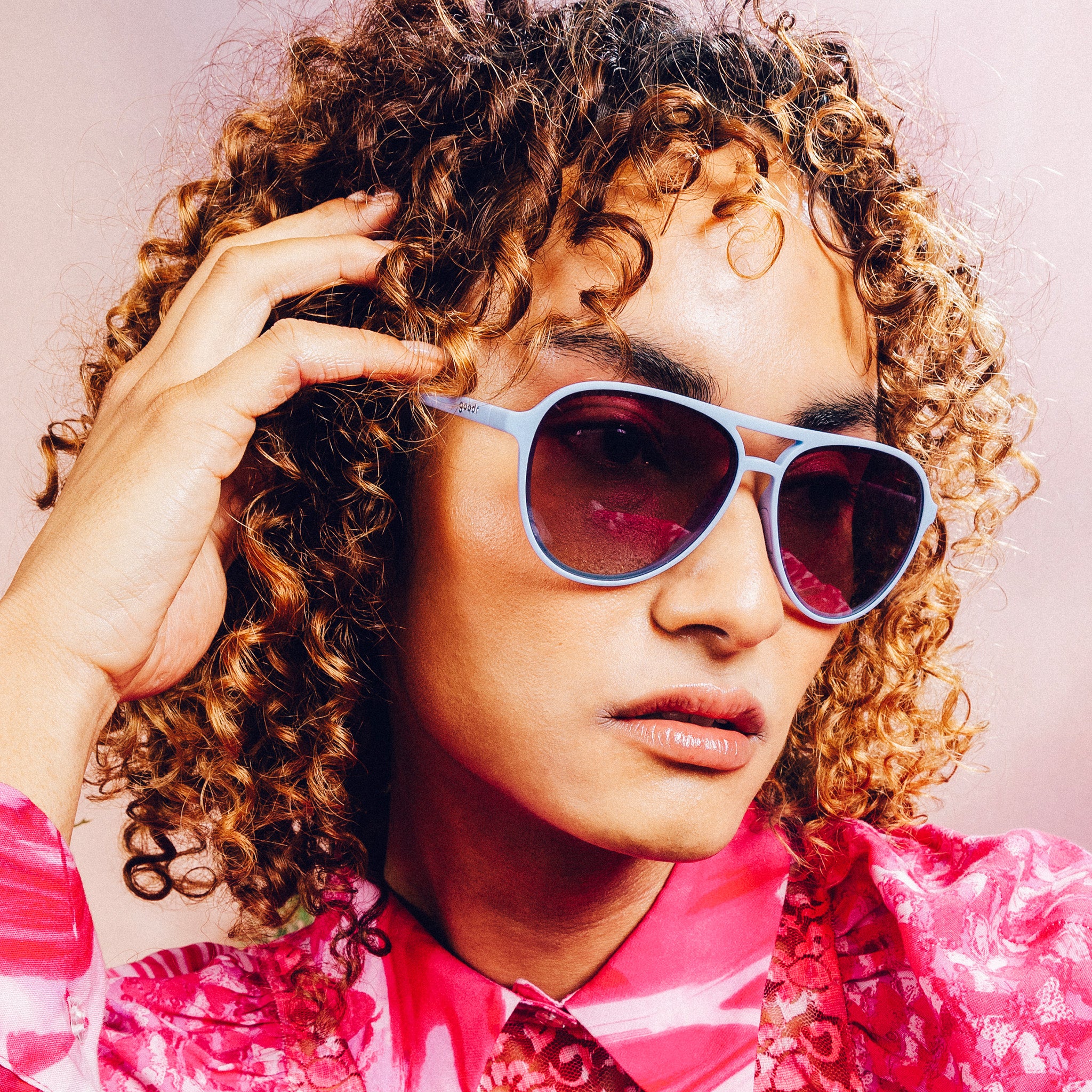 Woman posing with light blue aviator sunglasses with purple gradient lenses.