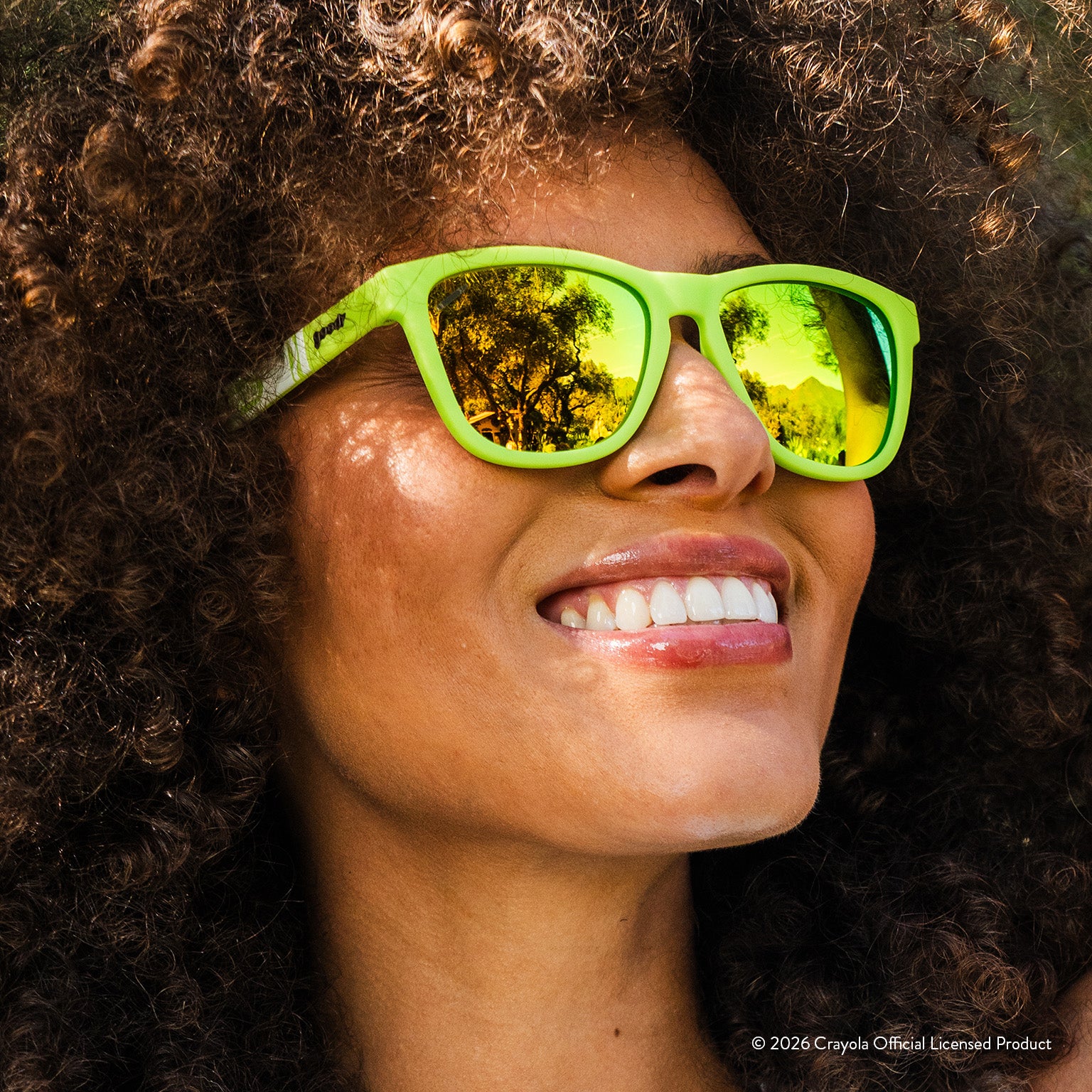 Woman smiling while wearing yellow green sunglasses w/ white Crayola marker pattern+green yellow reflective lenses.