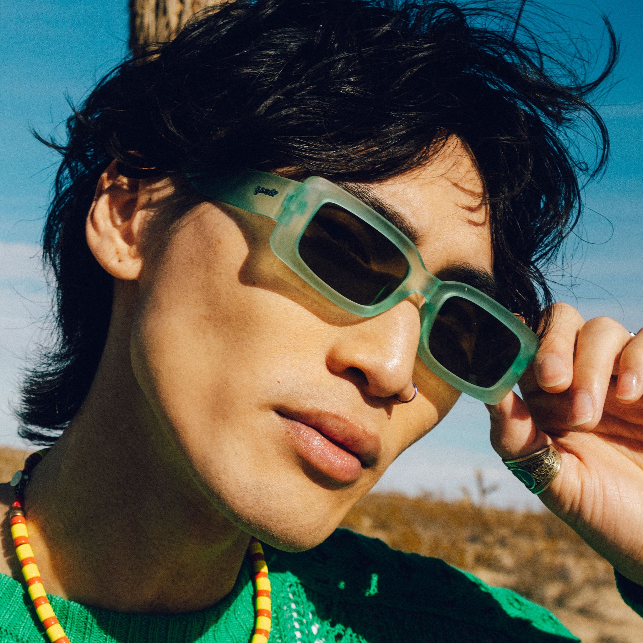 Man wearing and posing with translucent light green rectangular sunglasses with green lenses.