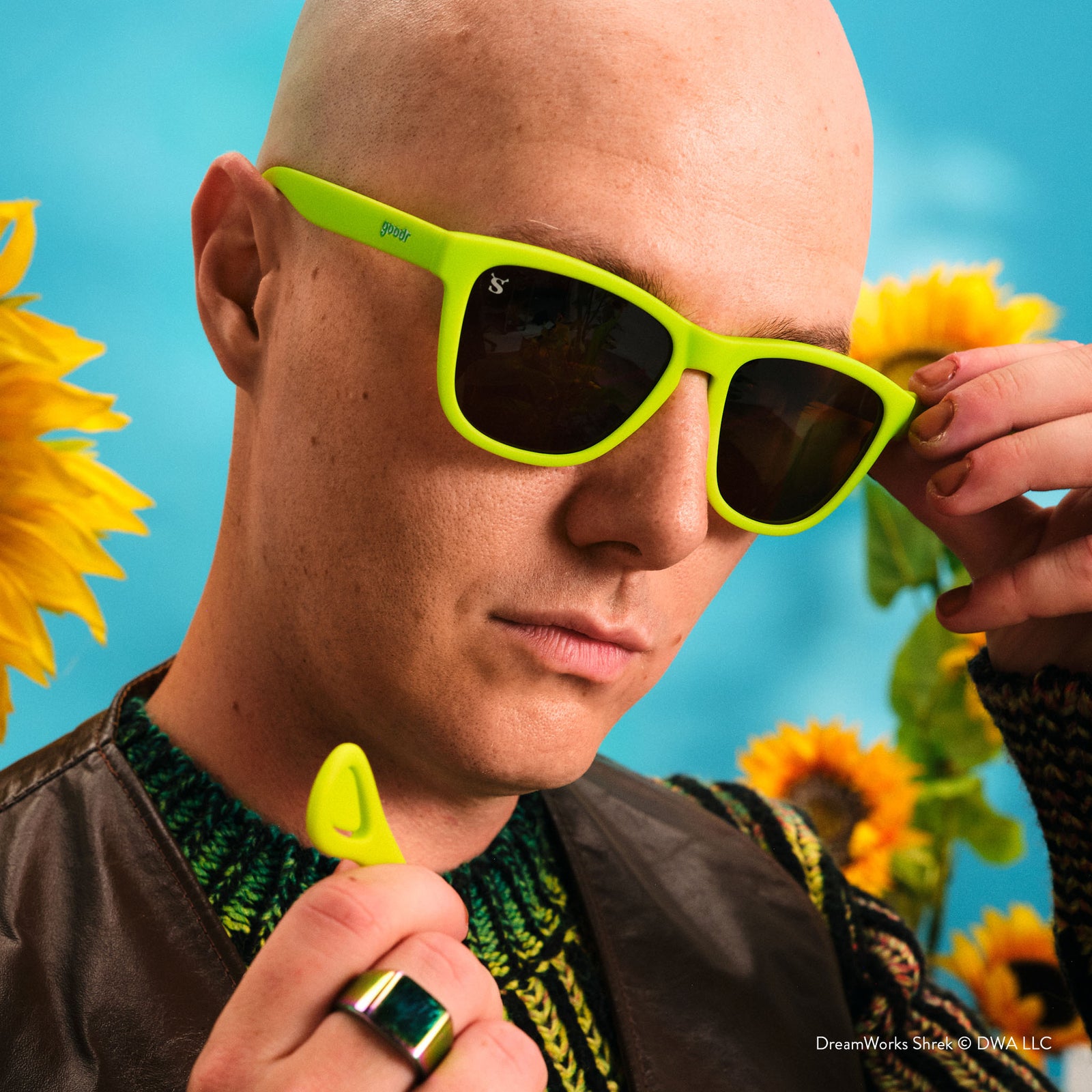 Person wearing bright green sunglasses with sunflowers in the background