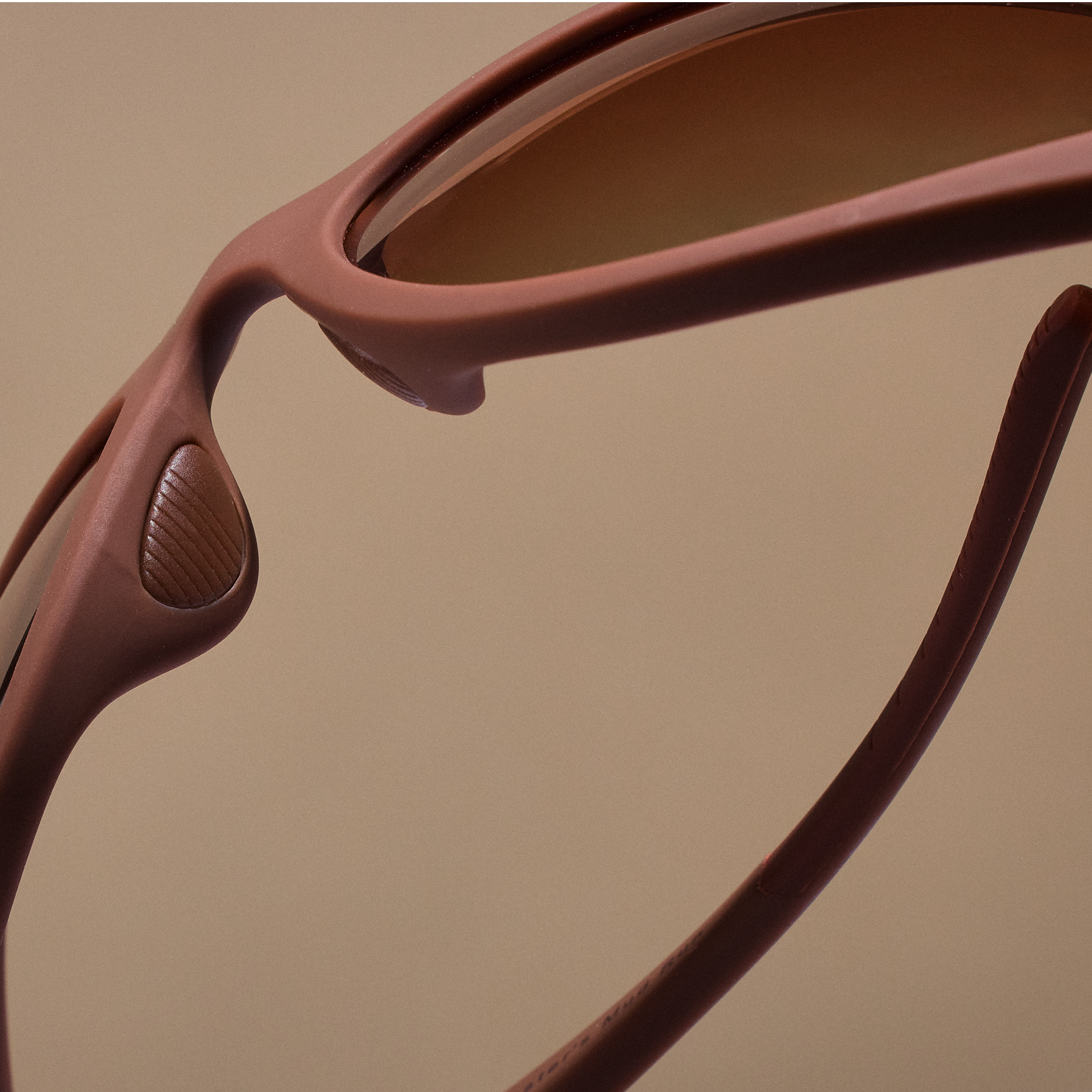Close-up of the nose pad on brown wraparound sunglasses with brown gradient lenses.