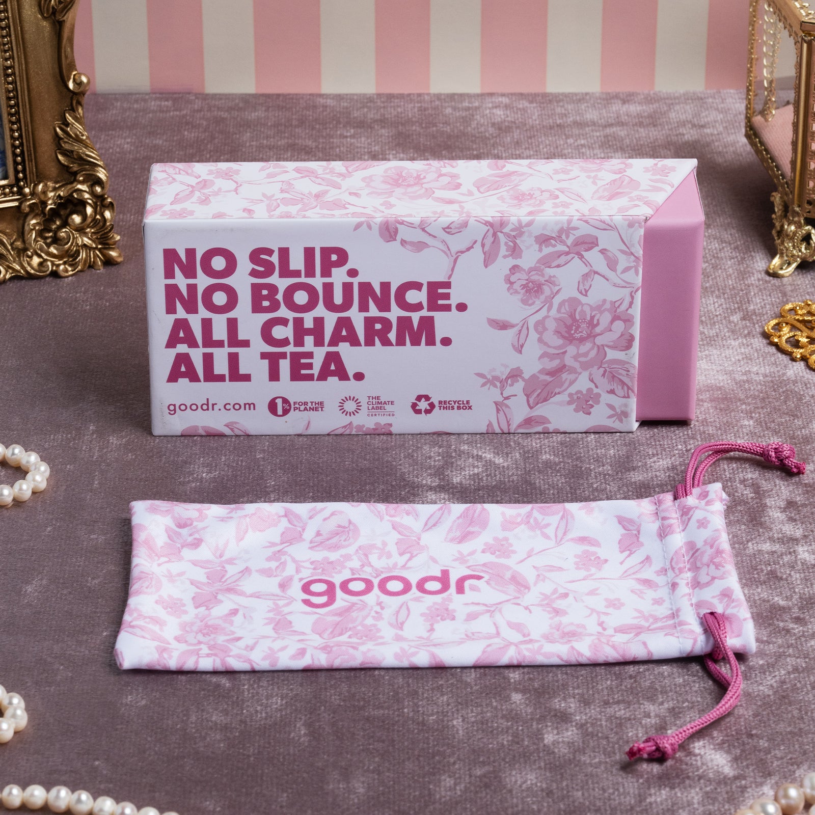 Custom packaging featuring a pink floral toile box and sunglasses pouch on top of a velvet pink tablecloth.