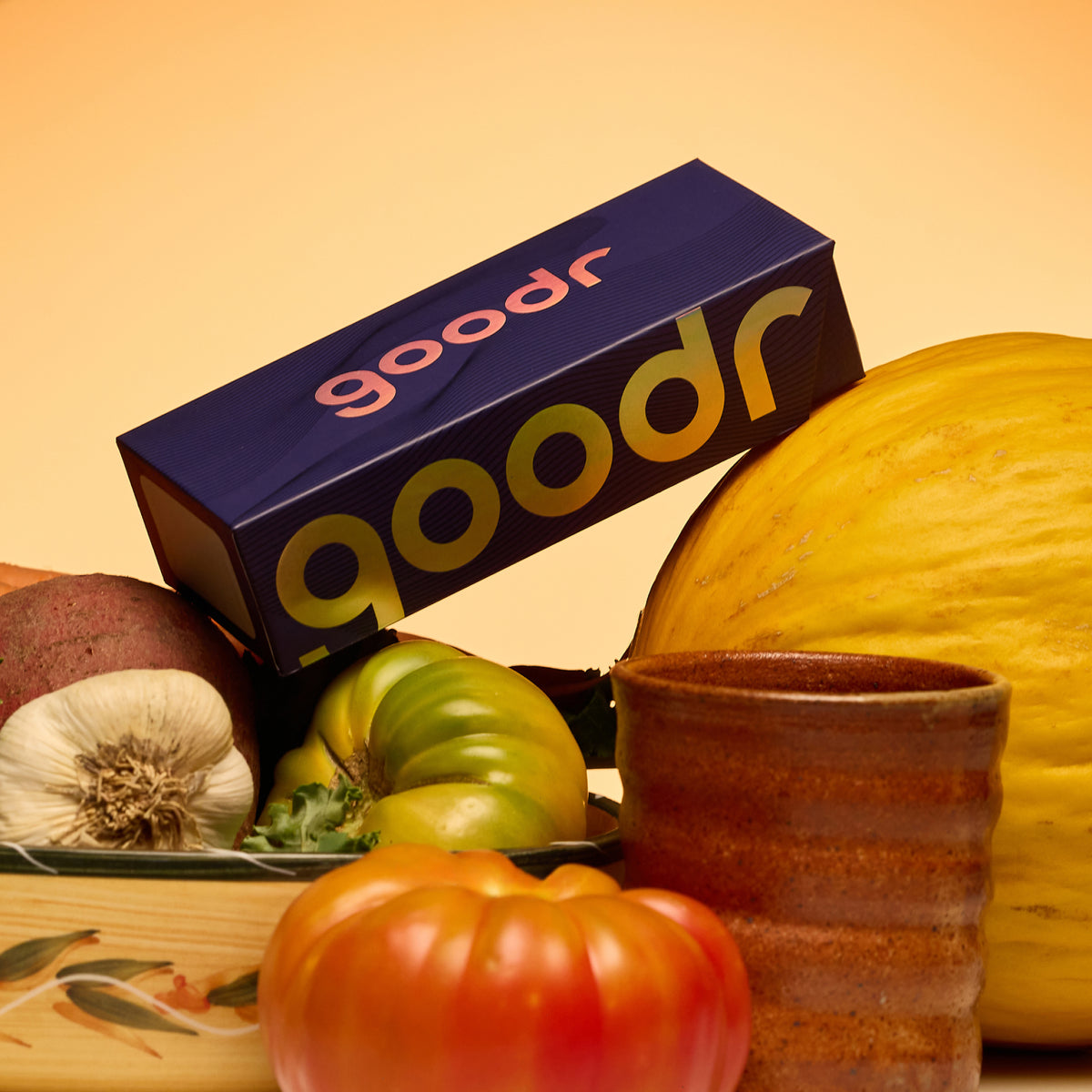Custom purple goodr packaging lying on top of harvested vegetables against a bright background.