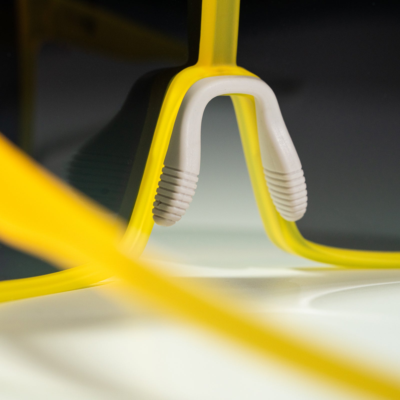Close-up shot of the nosepiece of a pair of yellow wrap sunglasses, photographed from behind.