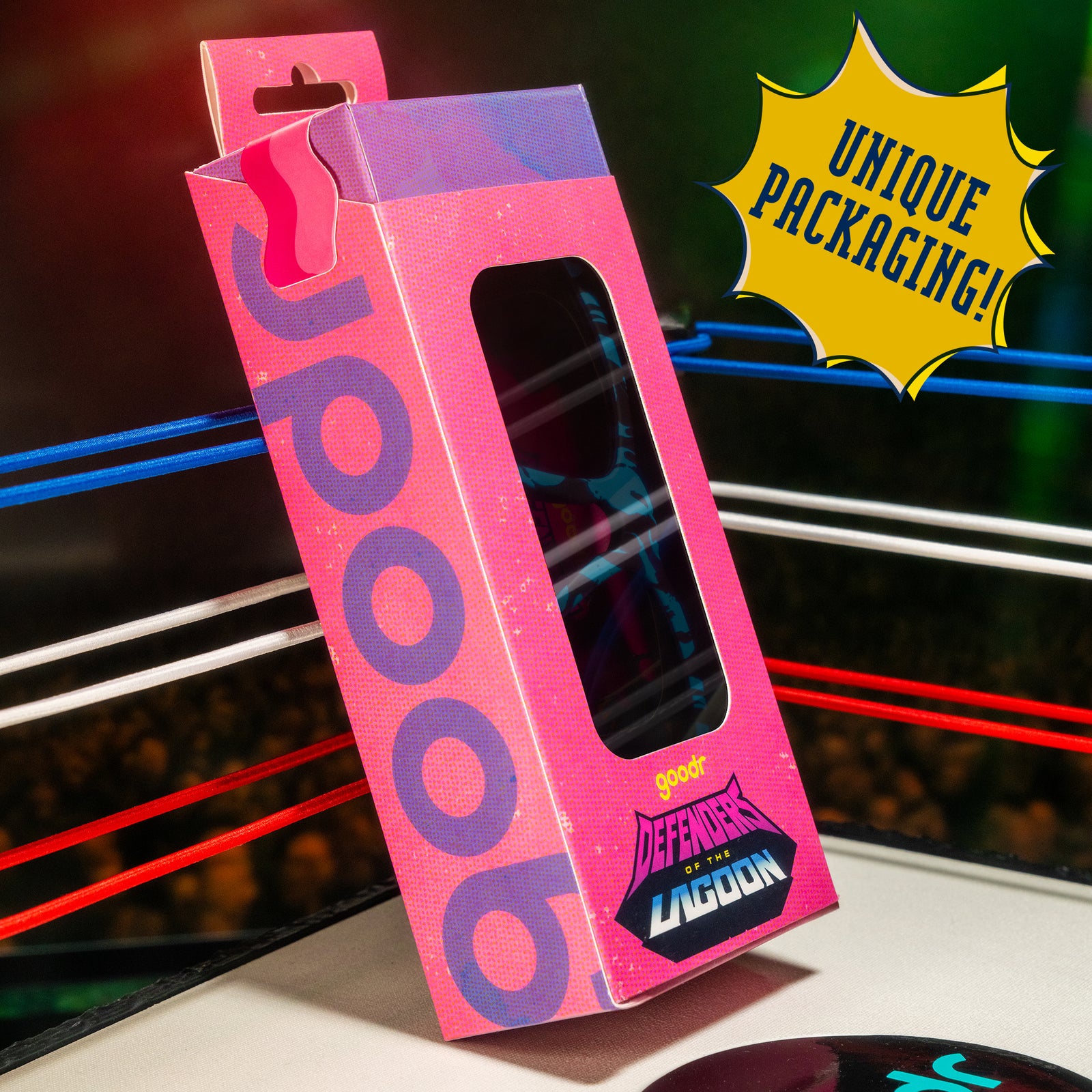 A hot pink and purple sunnies box that says Defenders of the Lagoon is posed in the corner of a miniature wrestling ring.