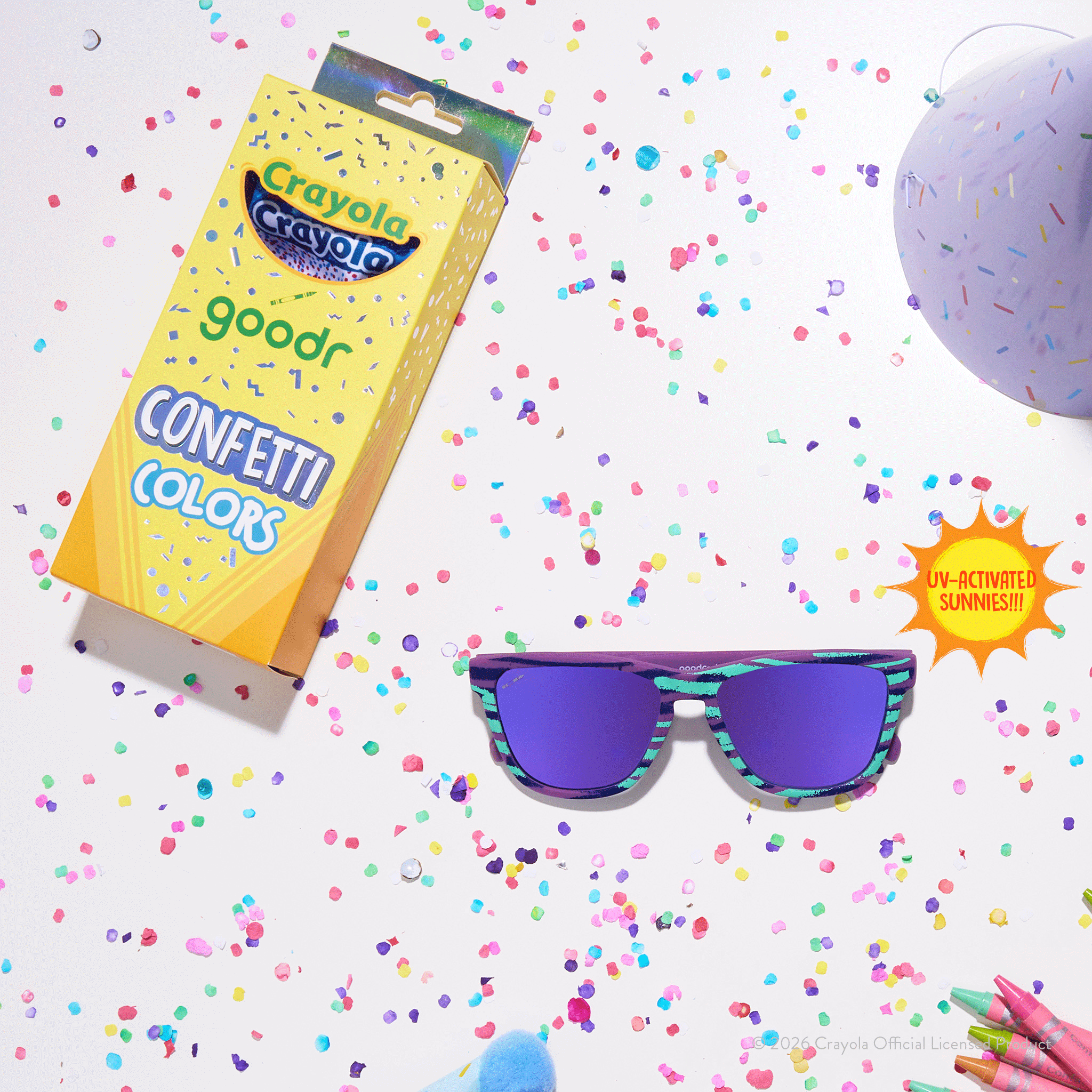 Green & purple Crayola goodr shades next to Confetti Colors Crayola box packaging, colorful confetti & party supplies.