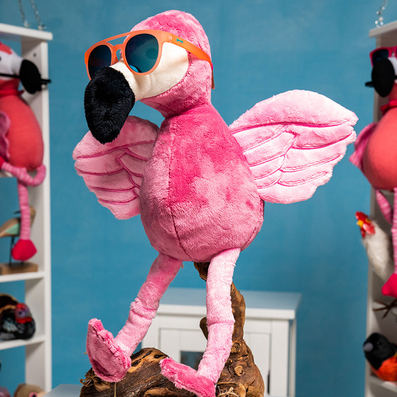 A fluffy stuffed flamingo spreads its wings while wearing round orange sunglasses with a double bridge and teal reflective mirrored lenses.