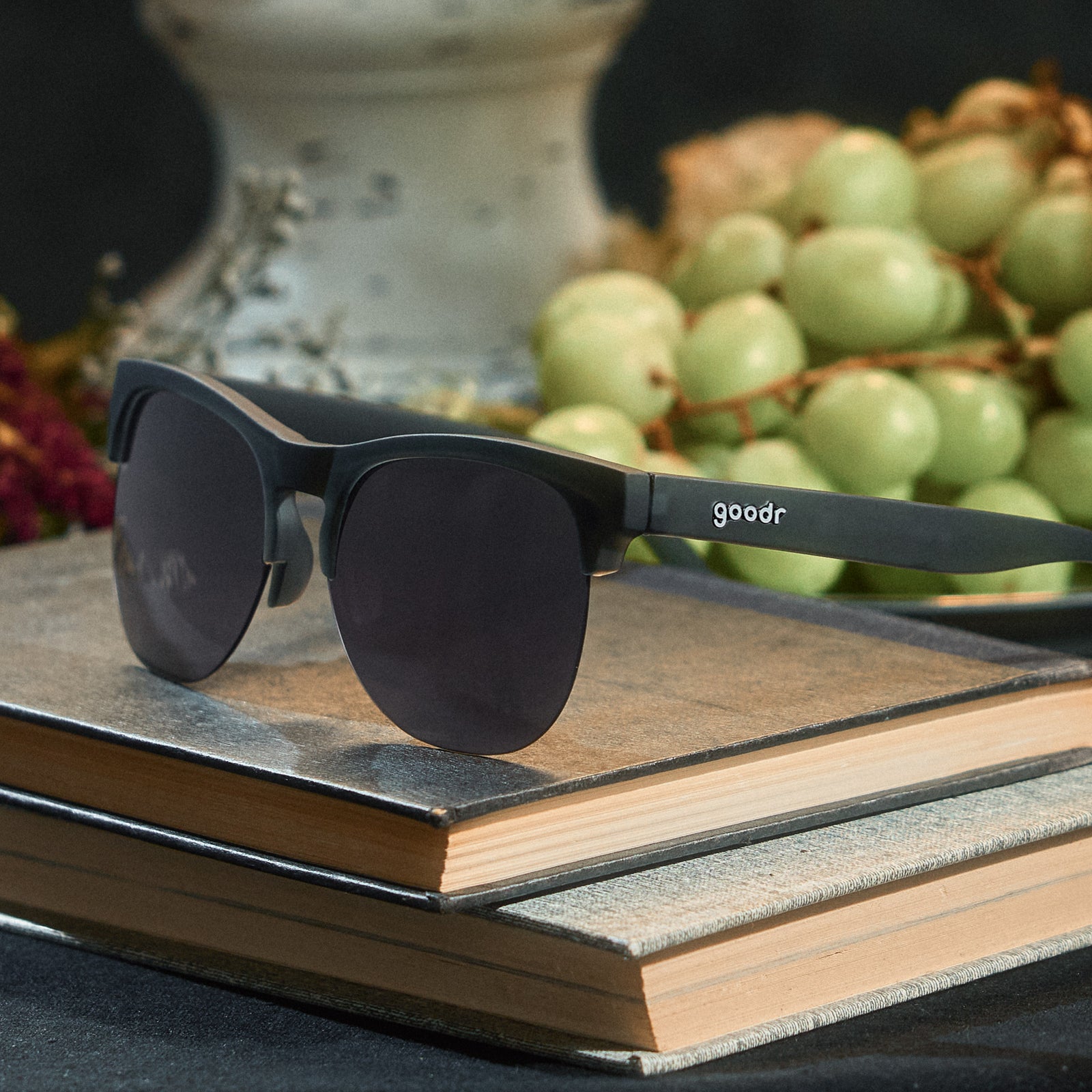 Three-quarter angle view of gray translucent half-rim frames featuring gradient gray lenses on top of stacked books.