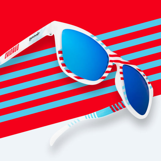 Right three-quarter angle view of blue and red striped sunglasses with blue reflective lenses in front of a striped background.