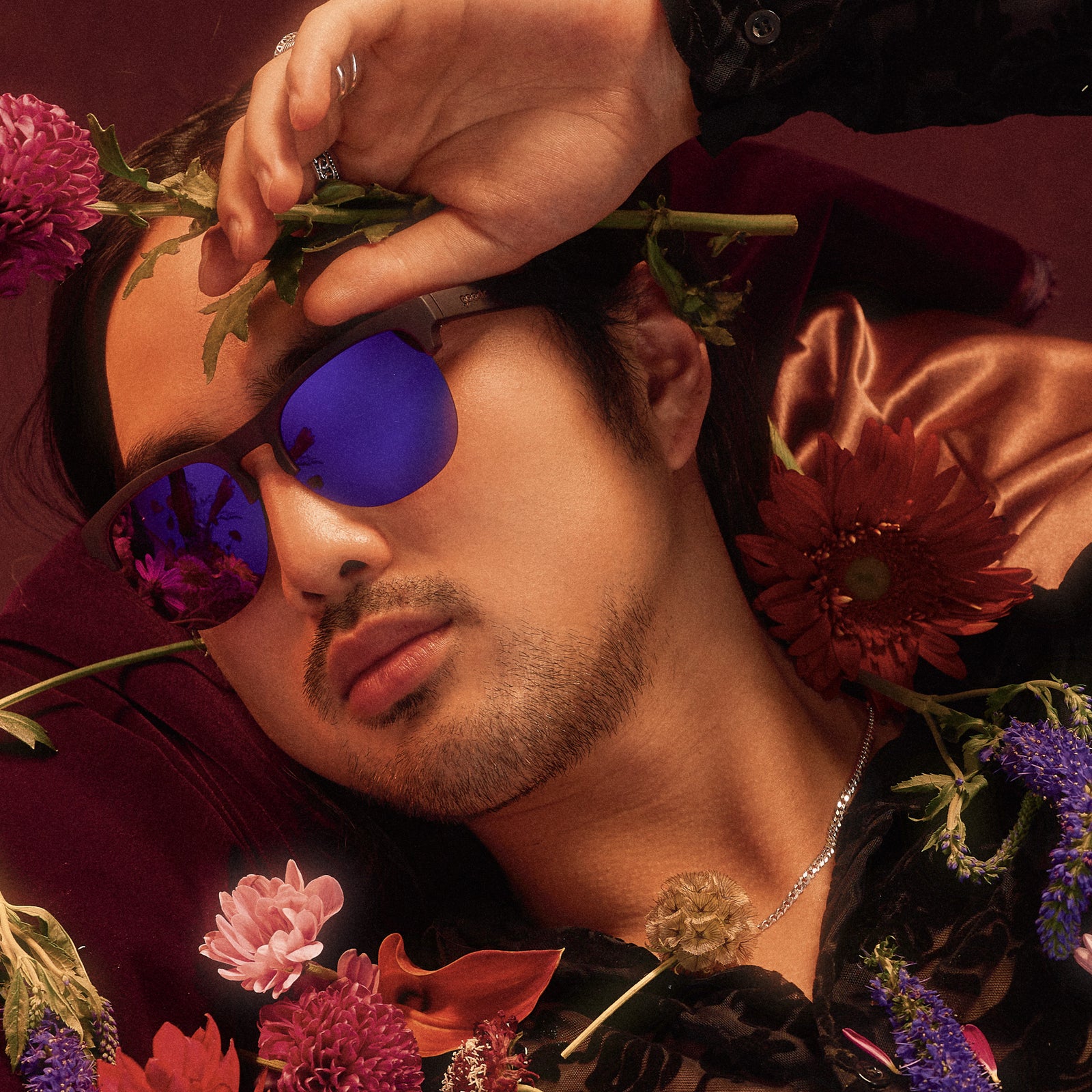 A man posing in translucent purple half-rim sunglasses with purple reflective lenses.